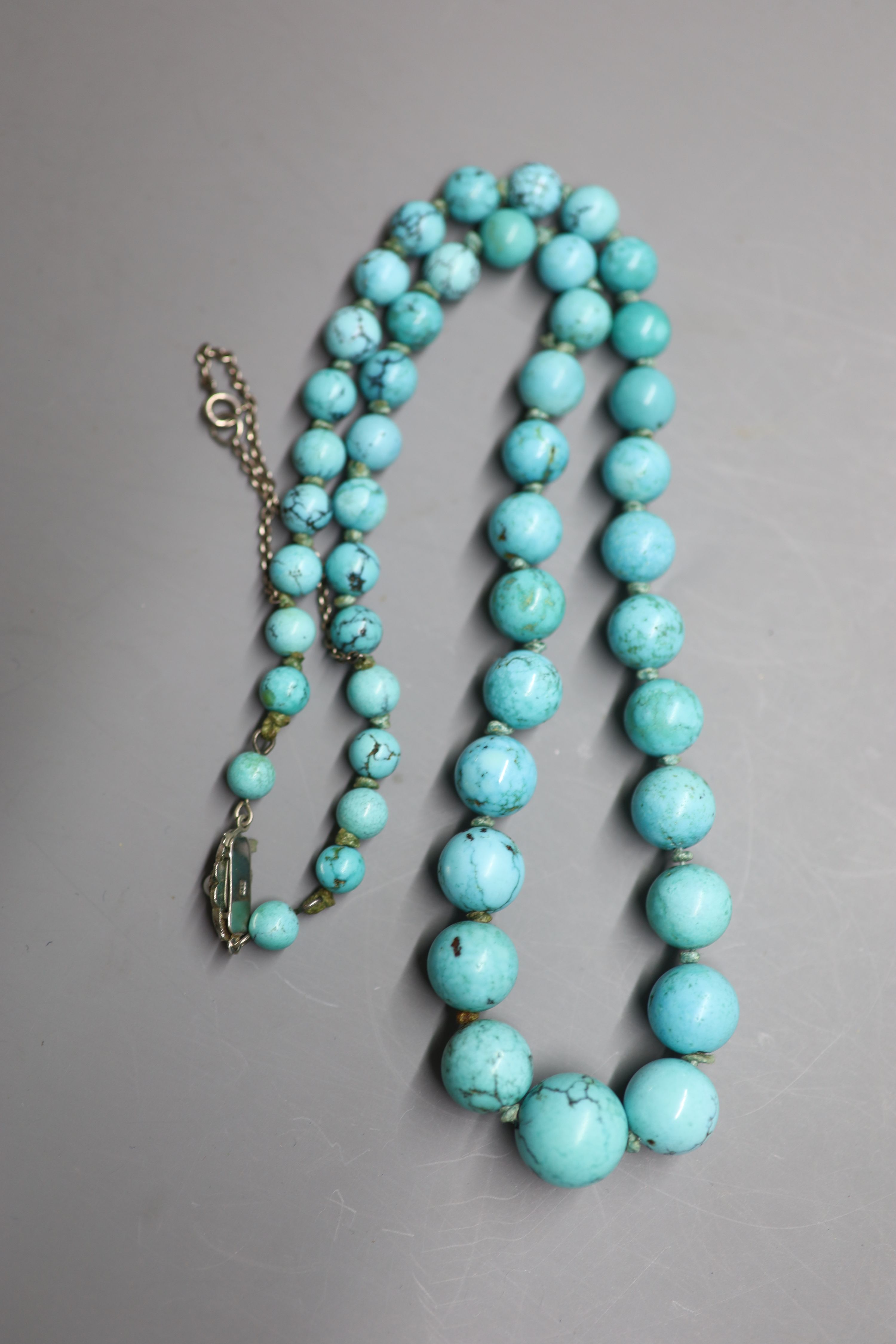 A continental graduated turquoise bead necklace, with marcasite and cultured pearl set white metal clasp, 57cm, gross 73 grams.